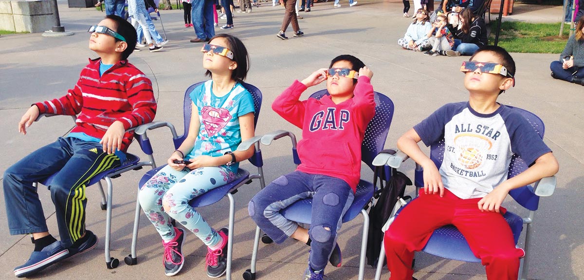 children watching eclipse with safety glasses at library